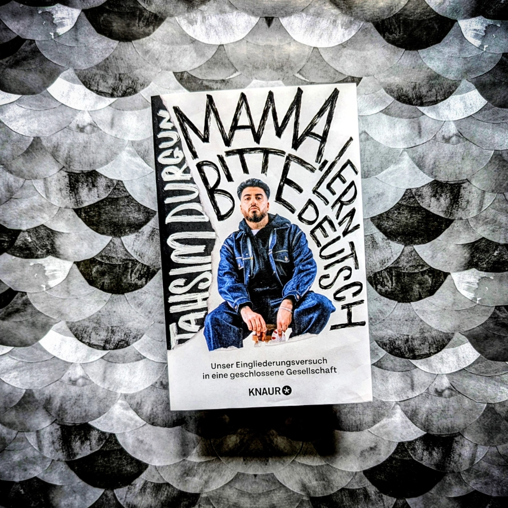 Das Foto zeigt die Paperback-Ausgabe des Sachbuchs „Mama, bitte lern Deutsch“ von Tahsin Durgun, die bei Knaur veröffentlicht wurde. Das Buch liegt auf einem gemusterten Papier-Hintergrund.
