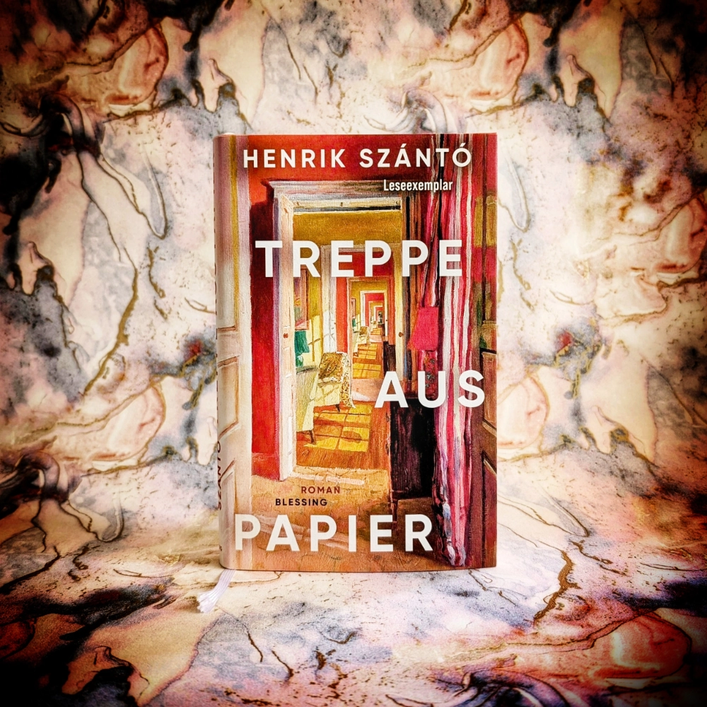 Das Foto zeigt die Hardcover-Ausgabe des Romans „Treppe auf Papier“ von Henrik Szántó, der im Blessing-Verlag veröffentlicht wurde. Das Buch steht vor einem gemusterten Papier-Hintergrund.