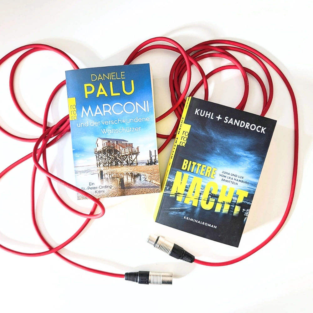 Das Foto zeigt die Bücher MARCONI UND DER VERSCHWUNDENE WATTSCHÜTZER von Daniele Palu, auch bekannt als Deutschlands schönster Krimiautor, und rechts daneben BITTERE NACHT vom Autorenduo (Nikolas) Kuhl und (Stefan) Sandrock. Beide Bücher liegen auf einem roten Mikrofonkabel.
