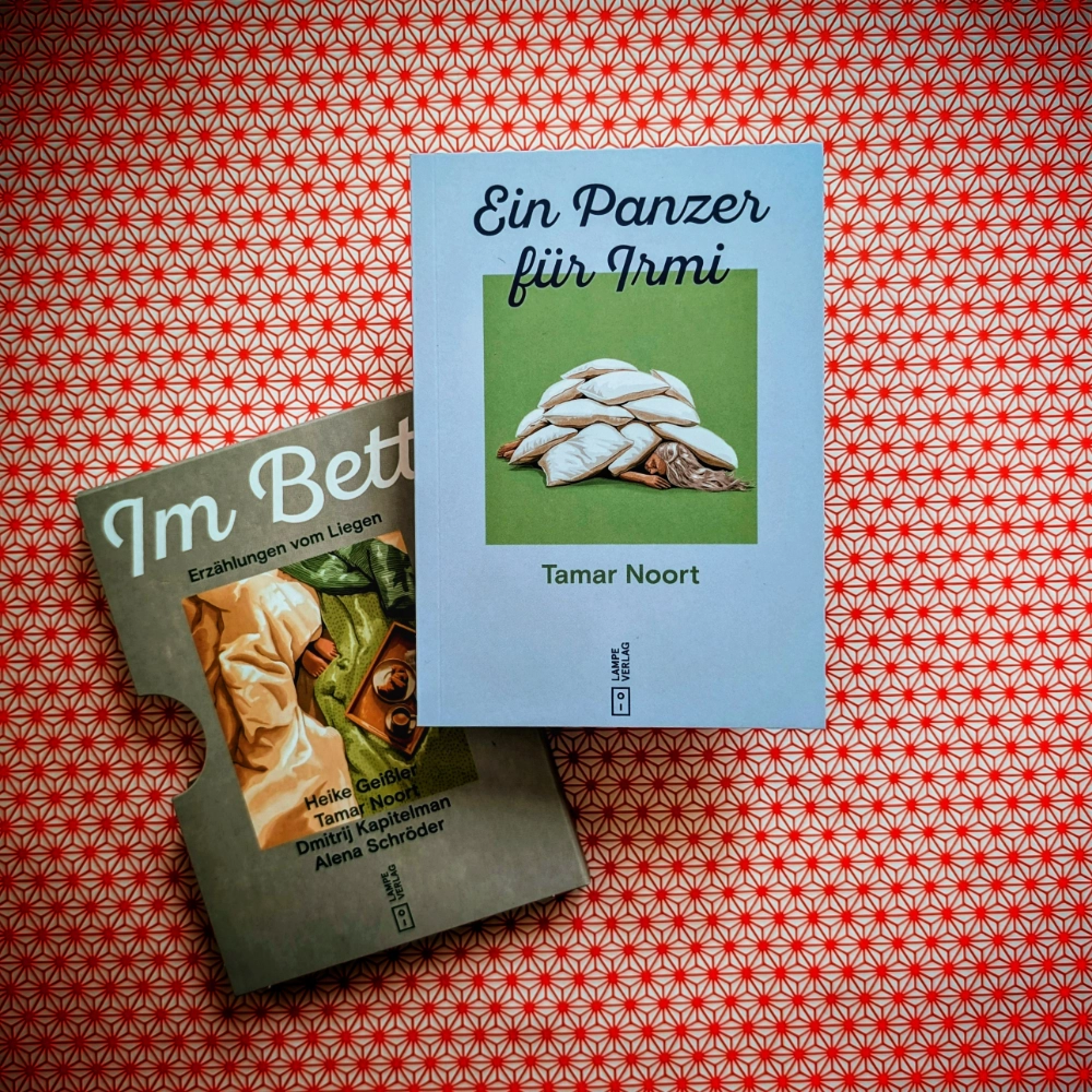 Das Foto zeigt das Minibuch „Ein Panzer für Irmi“ von Tamar Noort. Es ist Teil des Buchschubers „Im Bett – Erzählungen vom Liegen“, erschienen im Lampe Verlag. Das Minibuch und der Buchschuber liegen auf einem gemusterten Papierhintergrund.