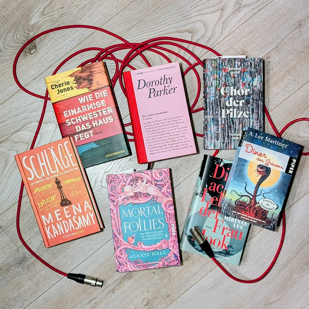 Das Foto zeigt diverse im Podcast erwähnte Bücher, die auf einem Mikrofonkabel liegen: NEW YORK GESCHICHTEN von Dorothy Parker, DIE ACHT LEBEN DER FRAU MOOK von Merinae Lee, SCHLÄGE von Meena Kandasam und WIE DIE EINARMIGE SCHWESTER DAS HAUS FEGT von Cherie Jones, CHOR DER PILZE von Hiromi Gato, MORTAL FOLLIES von Alexis Hall und DINER DES GRAUENS von A. Lee Martinez.