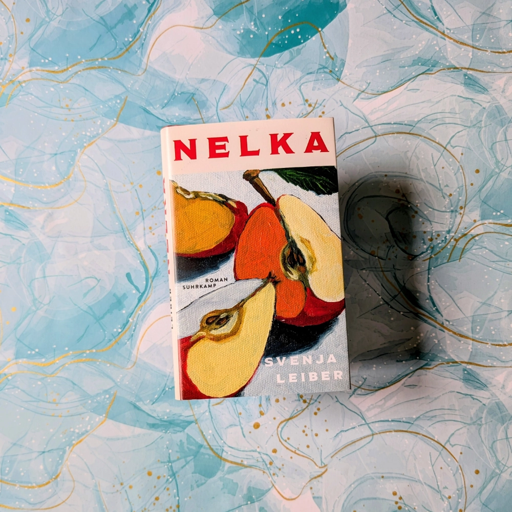 Das Foto zeigt die Hardcover-Ausgabe des Romans „Nelka“ von Svenja Lieber, der im Suhrkamp Verlag veröffentlicht wurde. Das Buch liegt auf einem gemusterten Papier-Hintergrund.