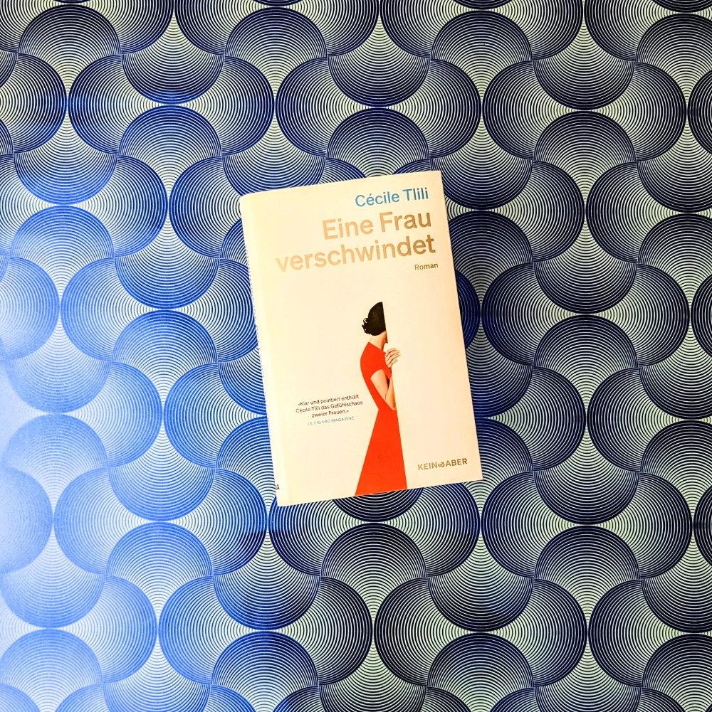 Das Foto zeigt das Buch "Eine Frau verschwindet" von Cécile Tlili; es liegt auf einem gemusterten Papierhintergrund.