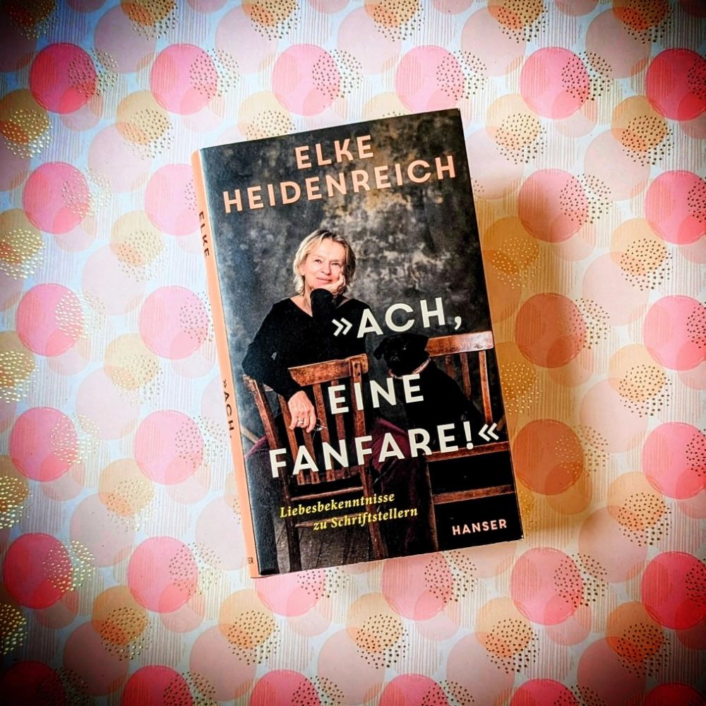 Das Foto zeigt das Buch "Ach, eine Fanfare!" von Elke Heidenreich; es liegt auf einem gemusterten Papierhintergrund.